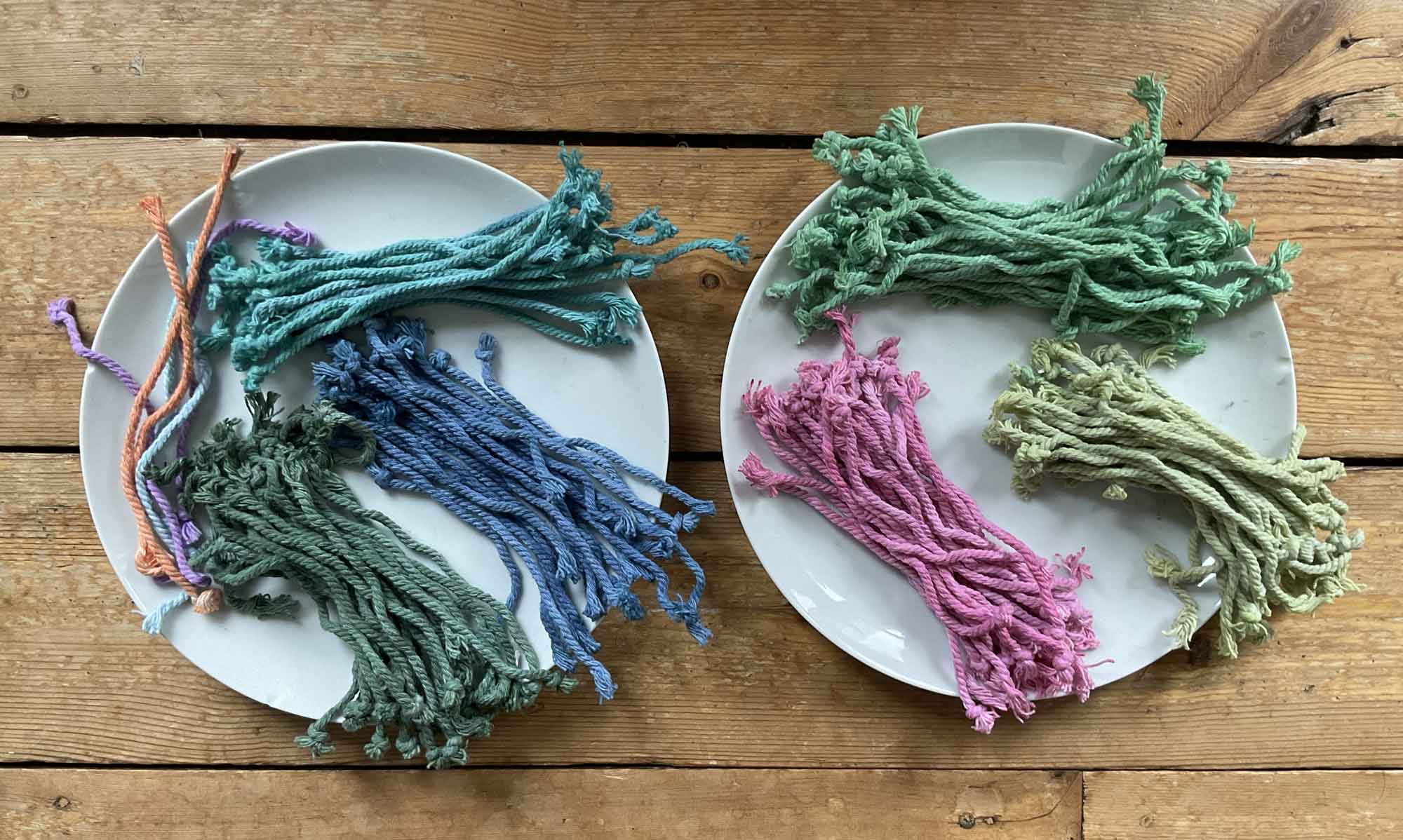 A collection of colorful yarns displayed in jars on a white table, showcasing various textures and hues.