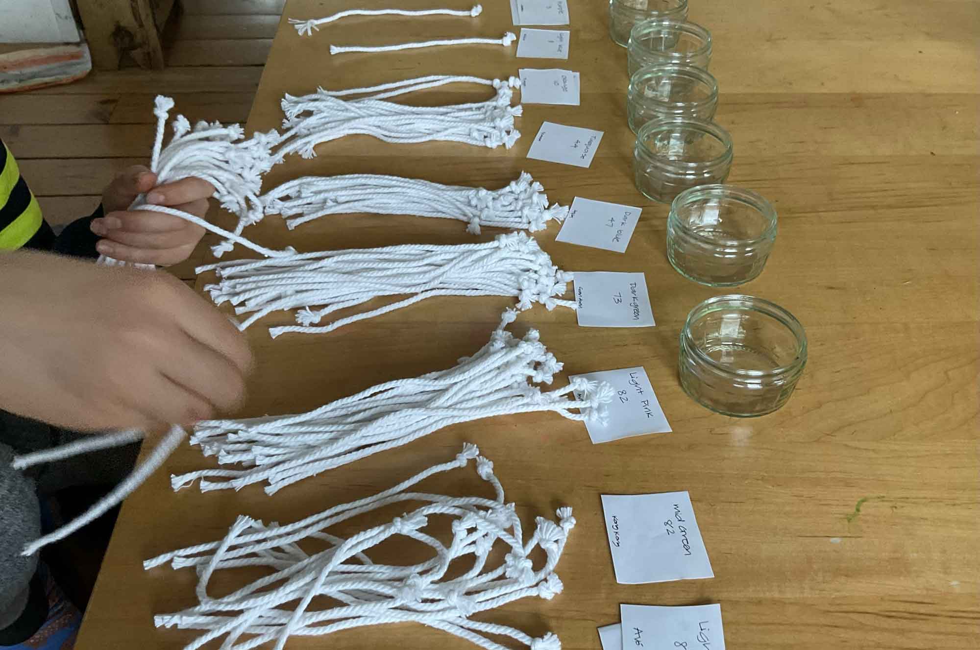 A young child is engaged in sorting white strings into piles on a table