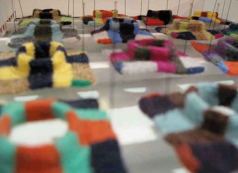 close up of small knitted pieces stuck down with pins